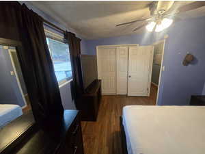 Bedroom featuring a textured ceiling, dark wood-type flooring, a closet, and a ceiling fan