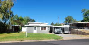 View of front facade featuring an attached carport, driveway, and brick siding