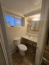 Half bathroom featuring a textured ceiling, vanity, and toilet