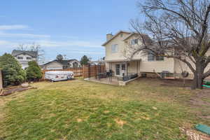 Back of property featuring a patio, a chimney, central air condition unit, a lawn, and fence