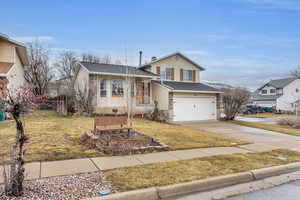 Split level home featuring a garage, fence, concrete driveway, and a front yard