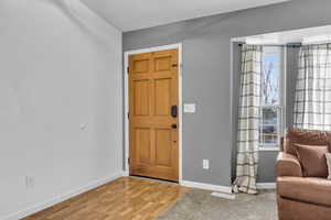 Foyer entrance with light wood finished floors, baseboards, and visible vents