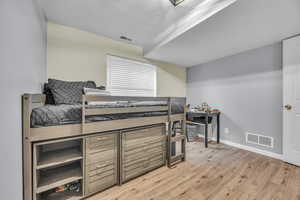 Bedroom featuring baseboards, visible vents, and wood finished floors