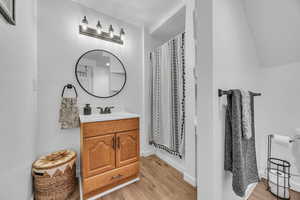 Full bath with baseboards, vaulted ceiling, wood finished floors, and vanity