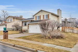 View of front of property with an attached garage, central AC, fence, concrete driveway, and a chimney