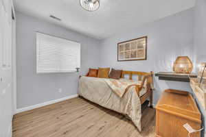 Bedroom with visible vents, baseboards, and wood finished floors