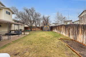 View of yard with an outbuilding, a patio area, a fenced backyard, and a shed