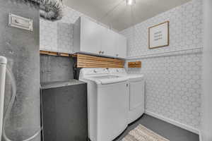 Laundry room with cabinet space, tile walls, and washer and dryer