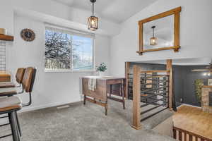 Office area featuring visible vents, baseboards, vaulted ceiling, a brick fireplace, and carpet