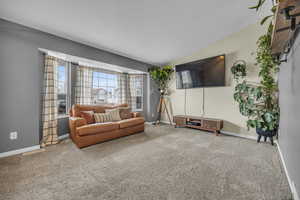 Carpeted living room featuring visible vents, baseboards, and vaulted ceiling