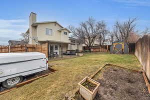 Rear view of property featuring a lawn, a chimney, a storage unit, an outdoor structure, and a patio area