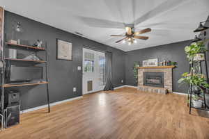 Living room featuring a brick fireplace, wood finished floors, visible vents, and baseboards