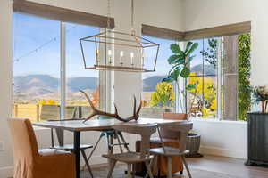 Dining area featuring a mountain view, a notable chandelier, baseboards, and wood finished floors
