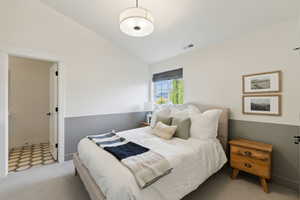 Bedroom with lofted ceiling, carpet floors, visible vents, and baseboards