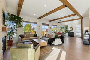 Living room featuring light wood finished floors, a fireplace, beamed ceiling, and recessed lighting