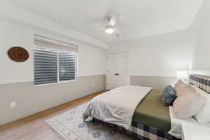 Bedroom with a ceiling fan, a closet, light wood-style flooring, and baseboards