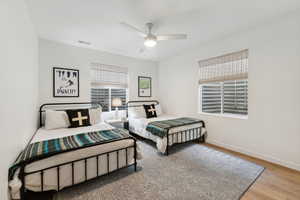 Bedroom featuring a ceiling fan, visible vents, baseboards, and wood finished floors