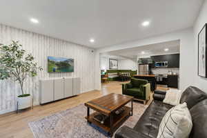 Living area with light wood-style floors, recessed lighting, and wallpapered walls