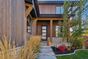 Property entrance with covered porch and stone siding