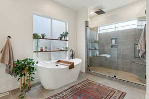 Bathroom featuring a shower stall, visible vents, baseboards, and a freestanding bath