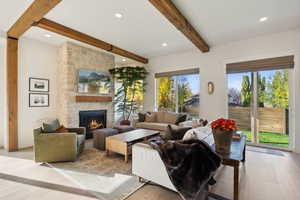 Living room featuring recessed lighting, beam ceiling, a fireplace, and light wood finished floors