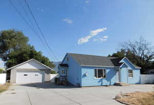 Single story home featuring a shingled roof, an outbuilding, fence, and a detached garage