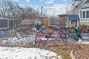 Yard covered in snow featuring a playground and fence