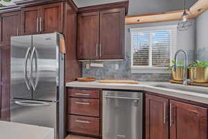 Kitchen with a sink, stainless steel appliances, tasteful backsplash, and light countertops