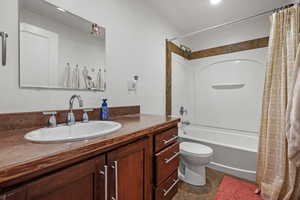 Bathroom featuring shower / bath combination with curtain, vanity, and toilet