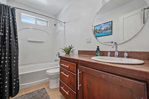 Bathroom featuring shower / bath combination with curtain, vanity, toilet, and tile patterned floors
