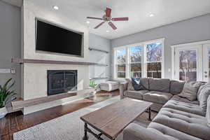 Living room with a large fireplace, french doors, wood finished floors, and recessed lighting