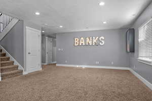 Empty room with carpet floors, recessed lighting, baseboards, and stairs