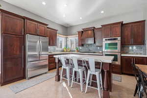 Kitchen with light tile patterned floors, a kitchen island, light countertops, appliances with stainless steel finishes, and custom exhaust hood
