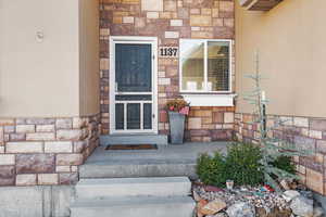 Doorway to property with stone siding and stucco siding