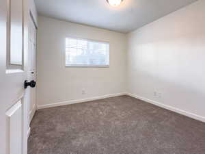 Spare room with dark colored carpet and baseboards