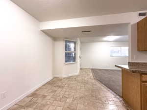 Unfurnished room with stone finish flooring, visible vents, and baseboards