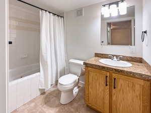 Bathroom with toilet, visible vents, vanity, tiled shower / bath, and tile patterned floors