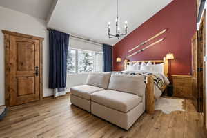 Bedroom featuring lofted ceiling, light wood-style flooring, and a notable chandelier