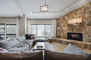 Living area with a fireplace, vaulted ceiling, a notable chandelier, and wood finished floors