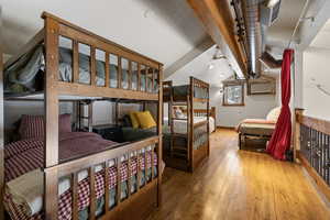 Bedroom with lofted ceiling with beams, wood-type flooring, and visible vents