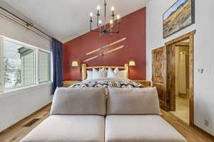 Bedroom featuring baseboards, wood finished floors, visible vents, and a notable chandelier