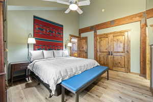 Bedroom with light wood-style floors, high vaulted ceiling, and a ceiling fan