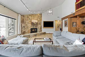 Living room featuring a fireplace, visible vents, an inviting chandelier, wood finished floors, and high vaulted ceiling