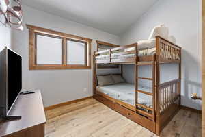 Unfurnished bedroom with baseboards, vaulted ceiling, and hardwood / wood-style floors