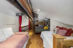 Bedroom with hardwood / wood-style flooring, vaulted ceiling, and a textured ceiling