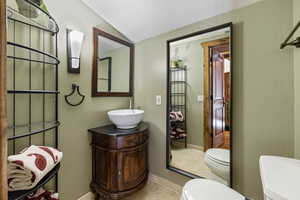 Bathroom featuring lofted ceiling, tile patterned flooring, toilet, vanity, and baseboards