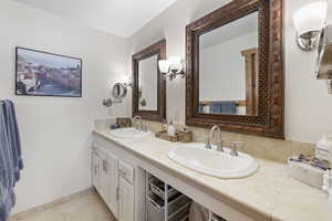 Bathroom featuring double vanity, tile patterned flooring, baseboards, and a sink