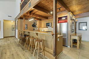 Kitchen featuring freestanding refrigerator, wooden ceiling, a kitchen breakfast bar, and beam ceiling