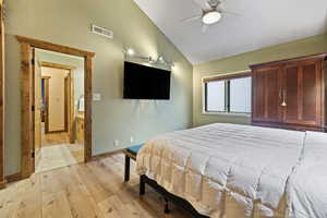 Bedroom featuring visible vents, baseboards, a ceiling fan, light wood-style flooring, and vaulted ceiling