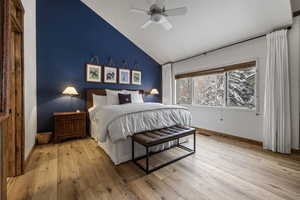 Bedroom featuring light wood-style flooring, baseboards, vaulted ceiling, and a ceiling fan